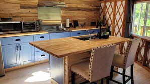 Una cocina compacta con una isla de madera, armarios azules y un ventanal grande.