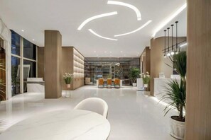 Un moderno vestíbulo de hotel con un mostrador de recepción de mármol, una zona de estar y una amplia estantería.