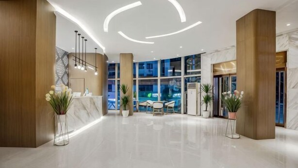 Un hall d’hôtel moderne avec un comptoir d’accueil, un espace salon et de grandes fenêtres.