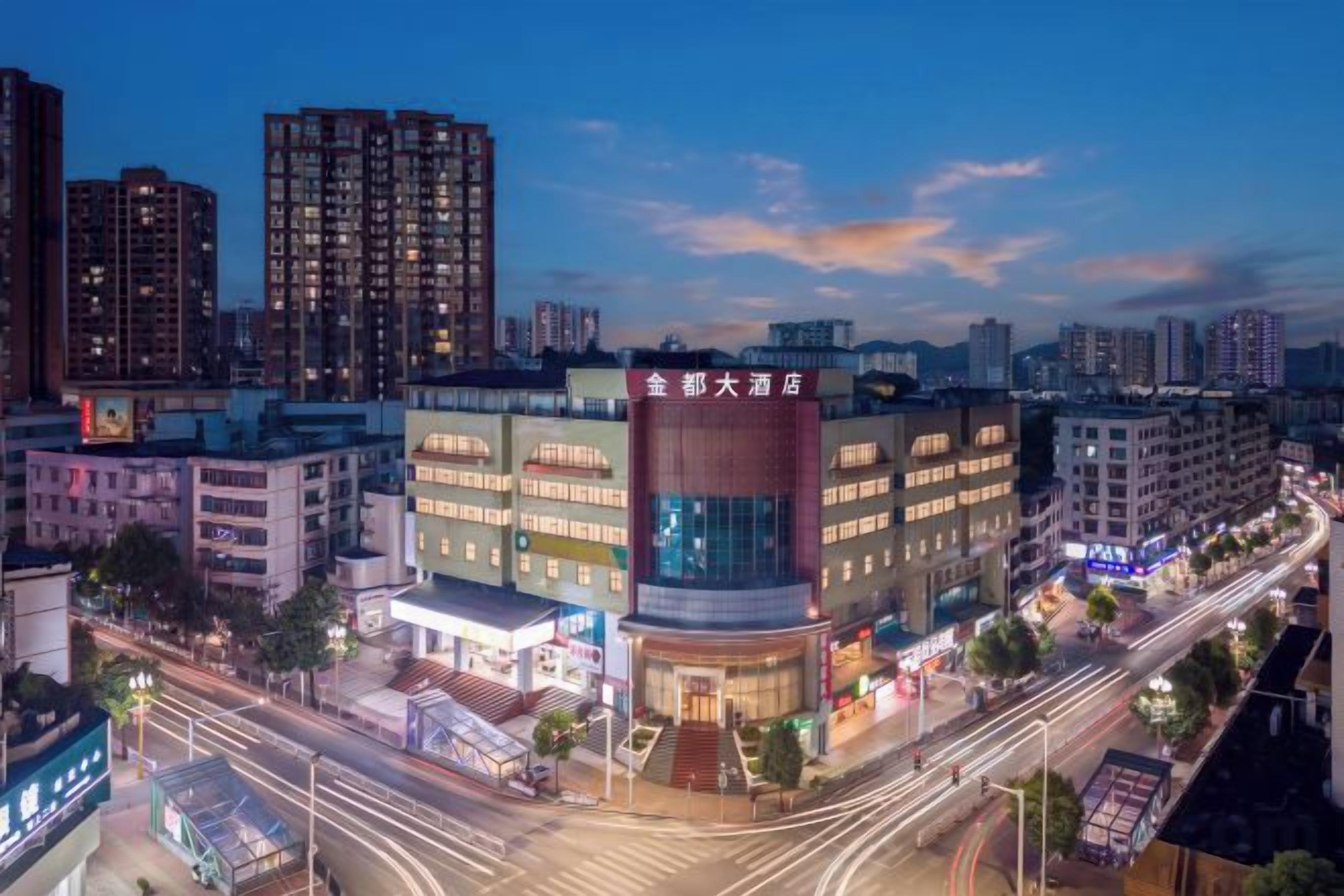 A multi-story hotel with a prominent red sign, surrounded by high-rise buildings and a busy street.