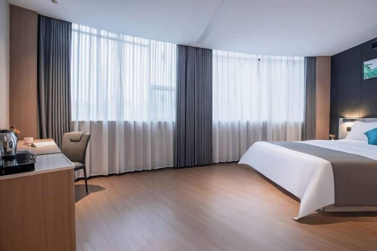A hotel room with a bed, a desk, and a chair.