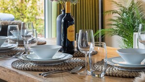 A dining table set with plates, bowls, cutlery, and wine bottles.