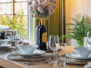 A dining table set with plates, bowls, cutlery, and wine bottles.