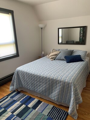 A bedroom with a bed, a bedside table, a lamp, a window, and a mirror. - Our Thunder Moon Farm Stay- sleeps 7, framed by wildflowers. 4 miles to GB. (Oneida)
