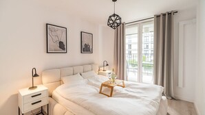 Une chambre à coucher comprenant un lit, des tables de chevet, une commode, une lampe suspendue et deux tableaux encadrés accrochés au mur.