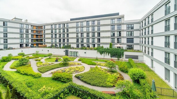 Un bâtiment moderne doté d’une cour intérieure agrémentée de jardins aménagés et de sentiers.