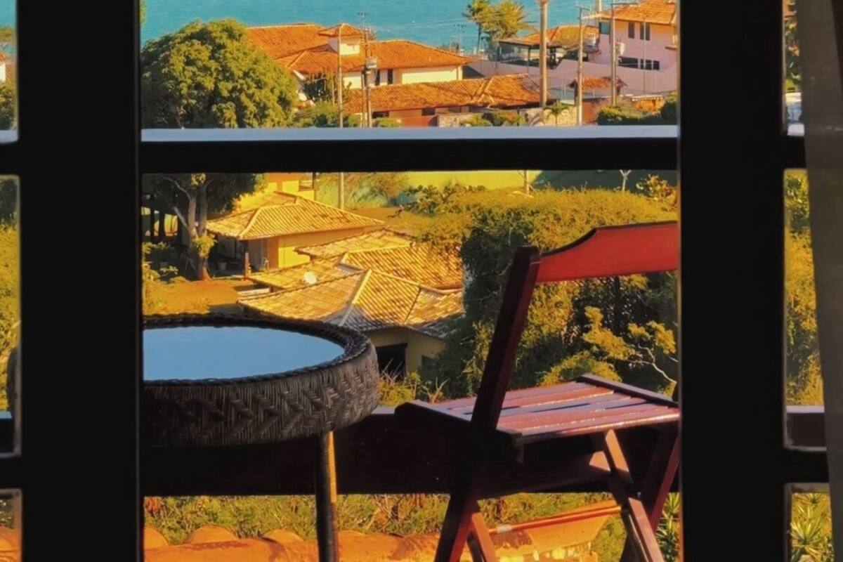 Vista desde una ventana con vista a una zona costera con casas, una masa de agua y colinas.