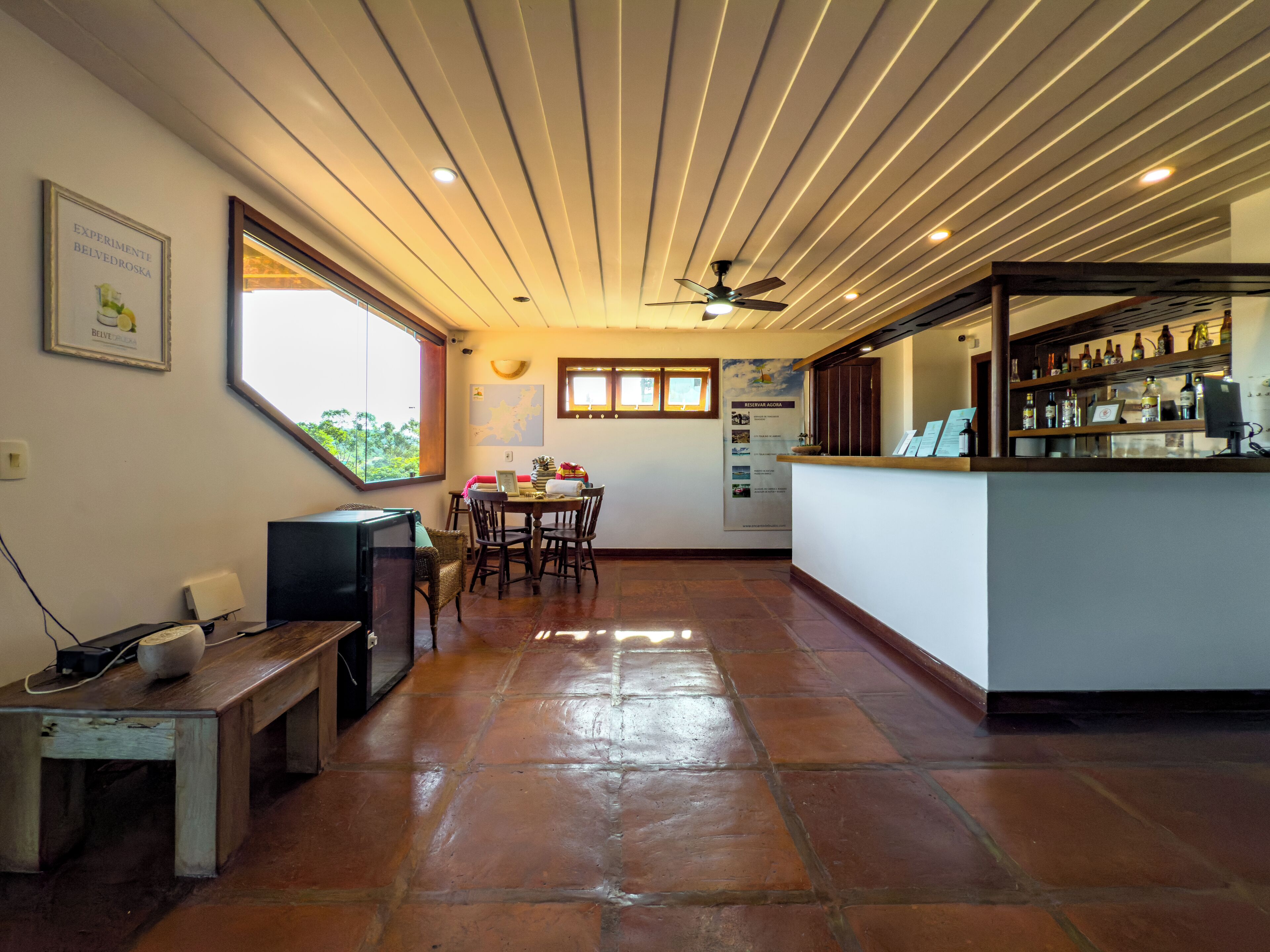 A spacious room with a dining area, a bar, and a ceiling fan.