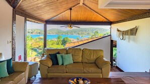 A spacious living room with a large window offering a scenic view of a coastal landscape. - Pousada Encanto de Buzios (Búzios)