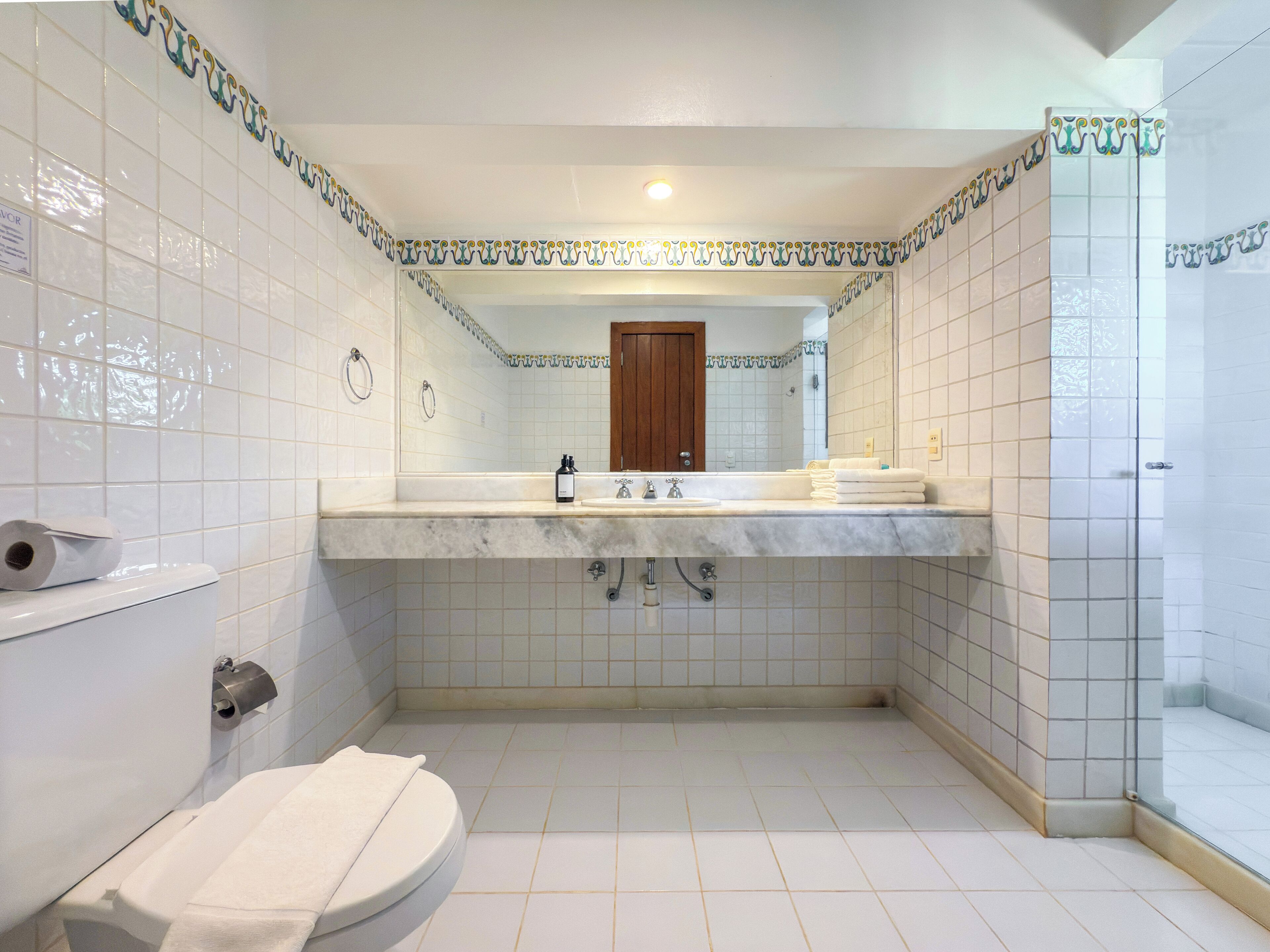 A bathroom with a white toilet, a sink with a mirror above it, and a shower area.