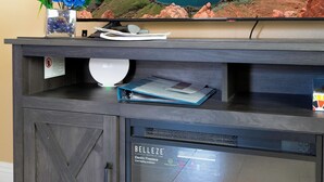 Un televisor de pantalla plana montado en un mueble de madera oscura con chimenea debajo.
