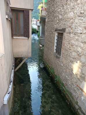 A narrow waterway flanked by stone buildings with visible windows and a small bridge.