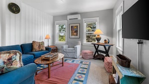 Un salon chaleureux avec un canapé bleu, un tapis à motifs et une petite table sur laquelle se trouve une lampe.