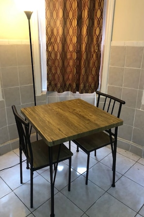 Une table à manger avec quatre chaises, un lampadaire et un rideau à motifs.
