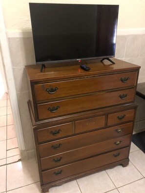 En trækommode med flere skuffer og et fladskærms-tv ovenpå.