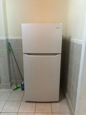 A white refrigerator in a corner of a room with tiled walls and floor. - Private 1-bedroom apartment, 15 minutes NYC, MetLife Stadium 20 mins (Union City)