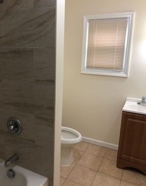 A bathroom with a toilet, a sink, and a shower area.