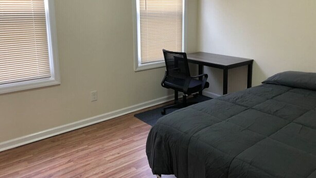 A bedroom with a bed, a desk, and two windows with blinds. - Private 3 bed, 1 bath apartment near EWR/NYC (Newark)