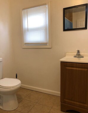 Ein Badezimmer mit Toilette, Waschbecken und einem Fenster mit Jalousien.