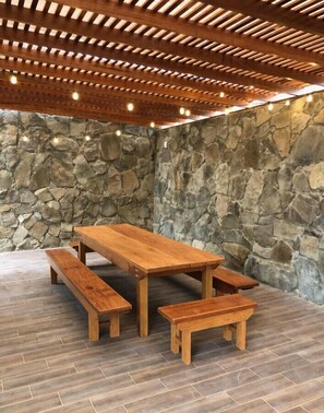 A wooden picnic table with benches in a stone-walled area.