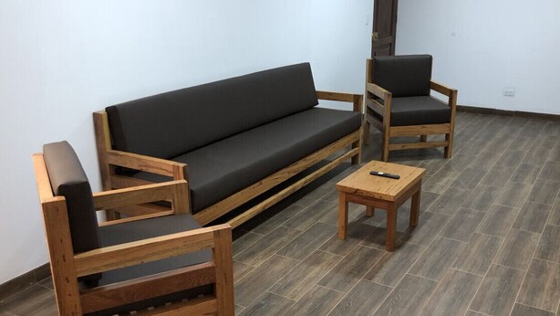 A room with a dark grey sofa, two wooden chairs, and a small wooden table. - Spacious 3-bedroom and 2 bathroom home with private pool and patio and free Wi-Fi (Calango)