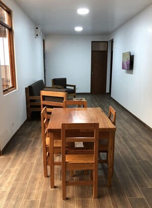 Une pièce comprenant une table et des chaises en bois, un canapé et une porte.