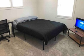 Une chambre à coucher avec un lit, un bureau, une chaise et un téléviseur.