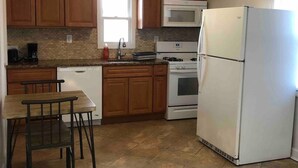 Una cocina con armarios de madera, un refrigerador blanco, un microondas, un horno y un lavavajillas.