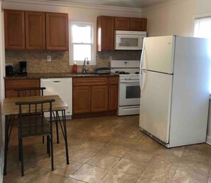 Una cocina con armarios de madera, un refrigerador blanco, un microondas, un horno y un lavavajillas.