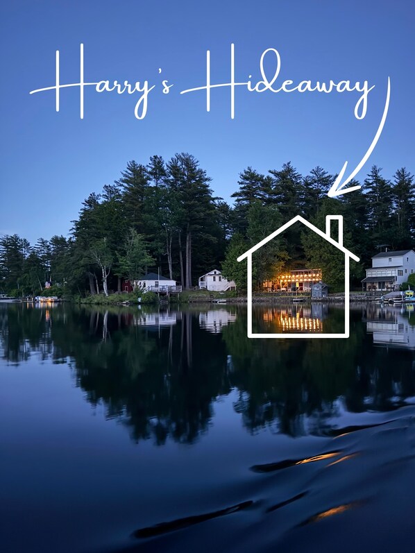 A lakeside view with a house marked as "Harry's Hideaway" reflected in the water.