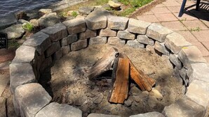 Un hogar de piedra con leña, rodeado por un borde de piedra.