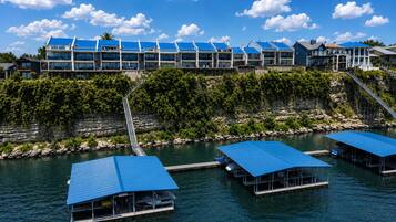 Ein Hotel am Wasser mit mehreren Gebäuden mit blauen Dächern, einem Steg mit Pontons und einer Steinschmalseite mit Bepflanzung.