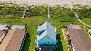 A beachfront property with a central building, multiple smaller structures, and a boardwalk leading to the beach.