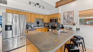 A modern kitchen with stainless steel appliances, wooden cabinets, and a granite countertop.