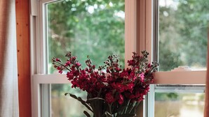 A wooden table with two bowls and a vase of flowers by a window.