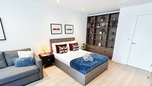 Un dormitorio moderno con una cama, un sofá, una mesita de noche, una estantería y un armario.