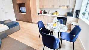 Una cocina moderna con armarios de madera, una mesa de comedor preparada para cuatro personas y un televisor al fondo.