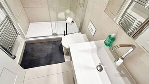 Un baño moderno con ducha, inodoro y lavamanos.