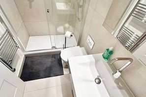 A modern bathroom with a shower, toilet, and sink.