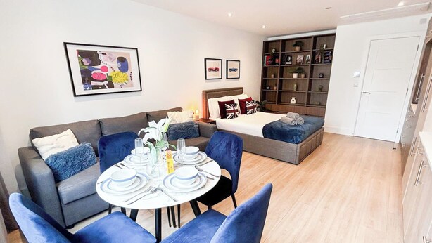 Una sala de estar moderna con un sofá, una mesa de comedor para cuatro personas y una estantería.