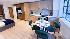 Een modern appartement met een eethoek, keuken en een slaapkamer met televisie.