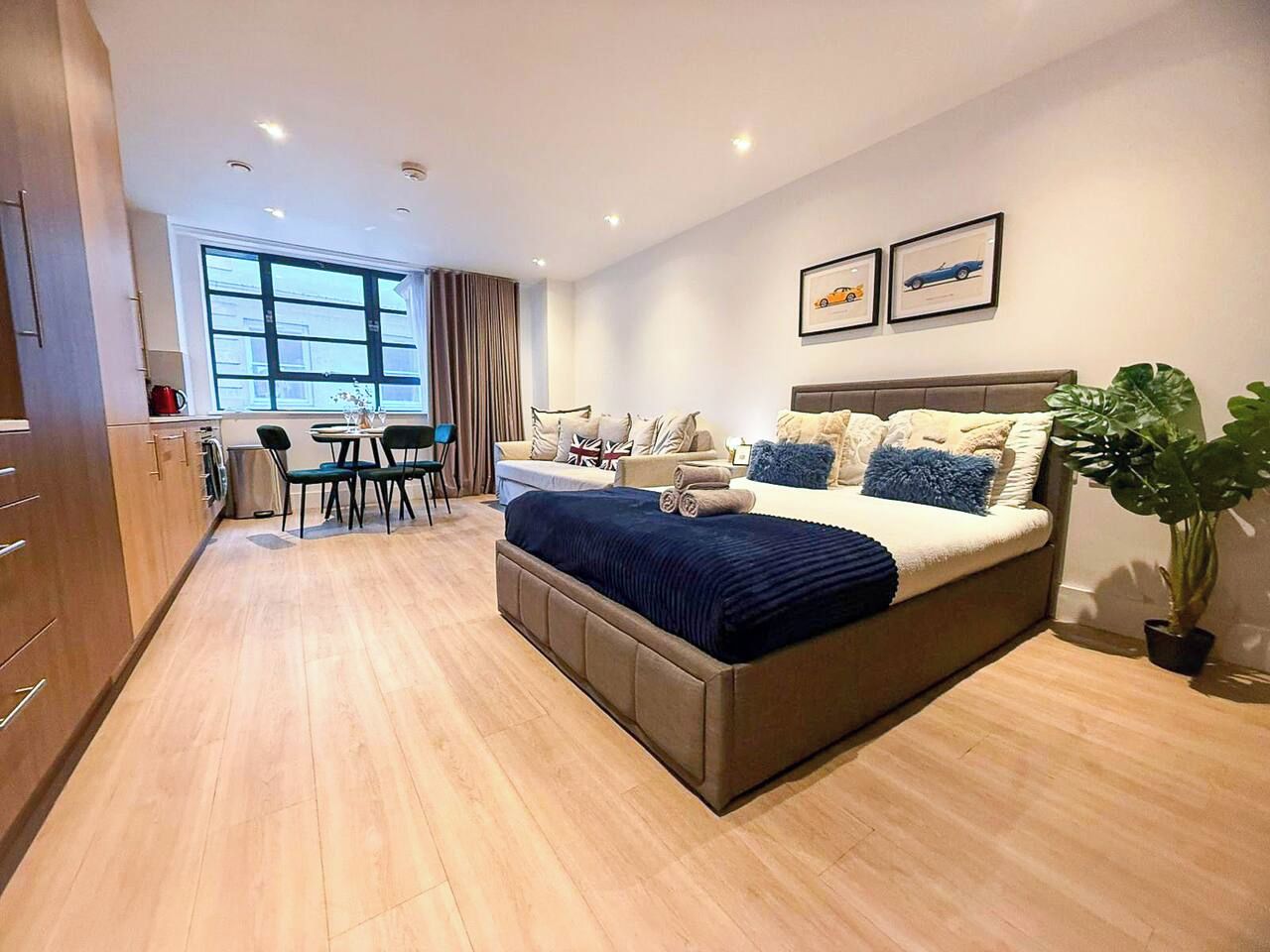 A modern hotel room with a large bed, a dining area, and a view of the city.