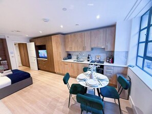 Een modern appartement met een eethoek, keuken en een slaapkamer met televisie.