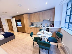 A modern apartment with a dining area, kitchen, and a living room.