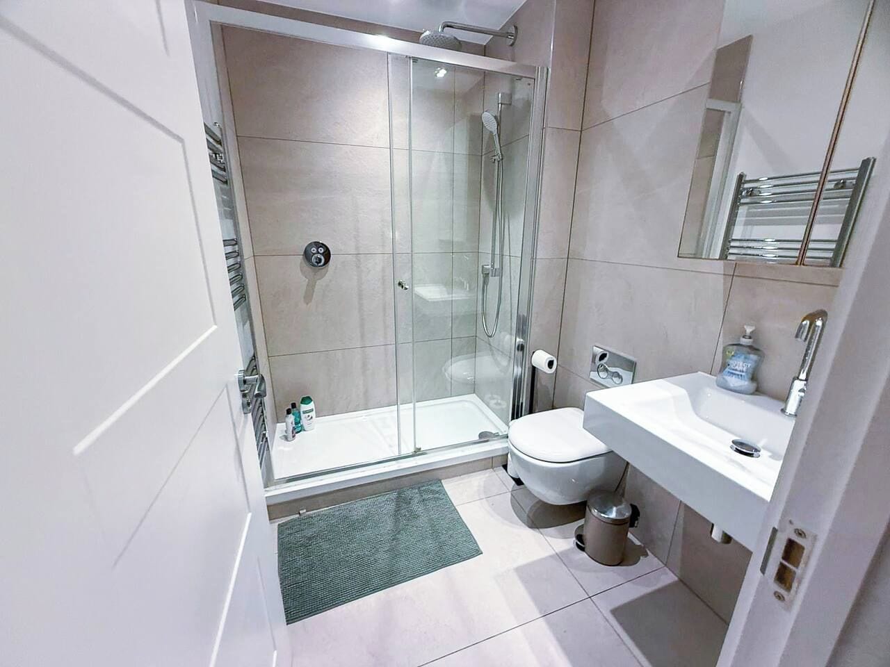 A modern bathroom with a glass-enclosed shower, a white toilet, and a sink with a mirror.