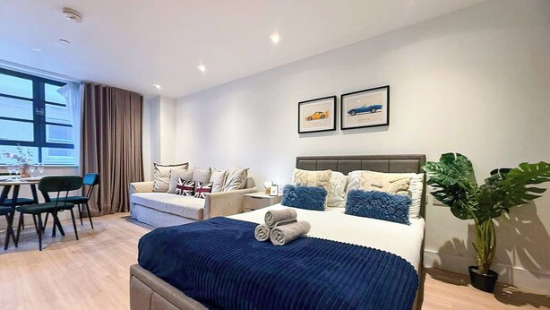 Een moderne hotelkamer met een groot bed, een bank, een zithoek en een kamerplant.