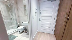 Een moderne badkamer met een douchecabine van glas, een toilet en een witte deur.