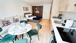 Un apartament modern amb zona de menjador, cuina i un saló acollidor amb llit.