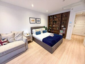 Une chambre moderne comprenant un lit, un canapé, une table de chevet et une bibliothèque intégrée.