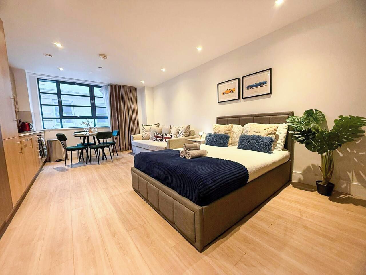 A modern hotel room with a large bed, a dining area, and a view of the city.